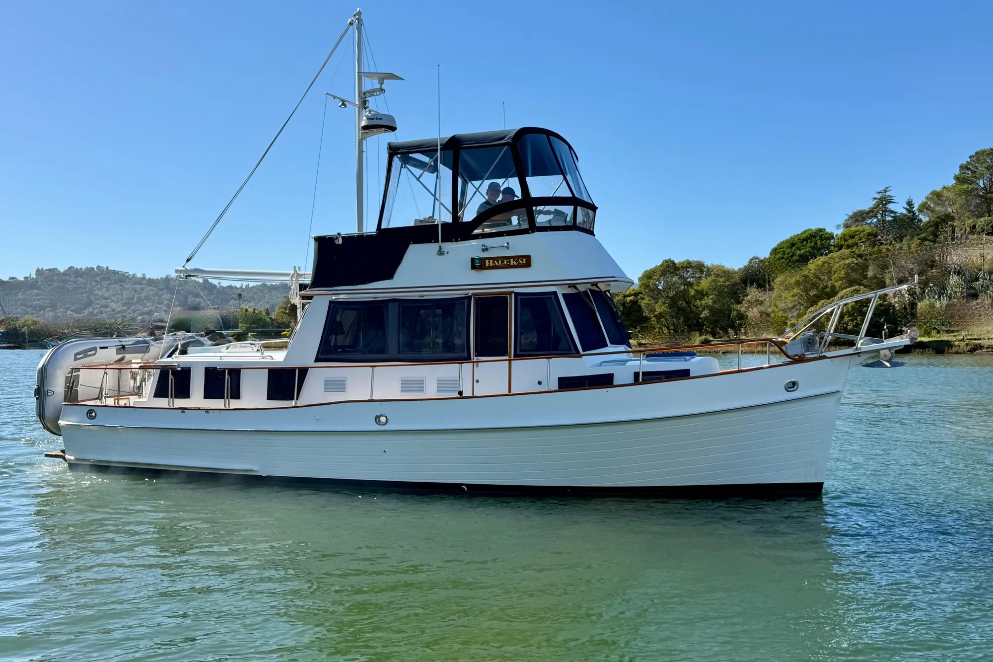1997 Grand Banks Classic yacht on calm water, surrounded by lush greenery.
