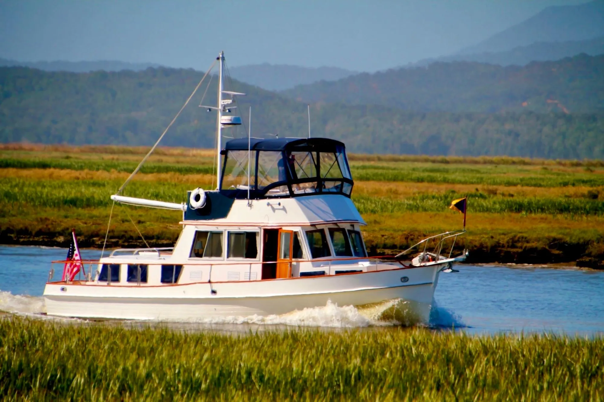 1997 Grand Banks Classic boat cruising through scenic waterway with lush green landscape.