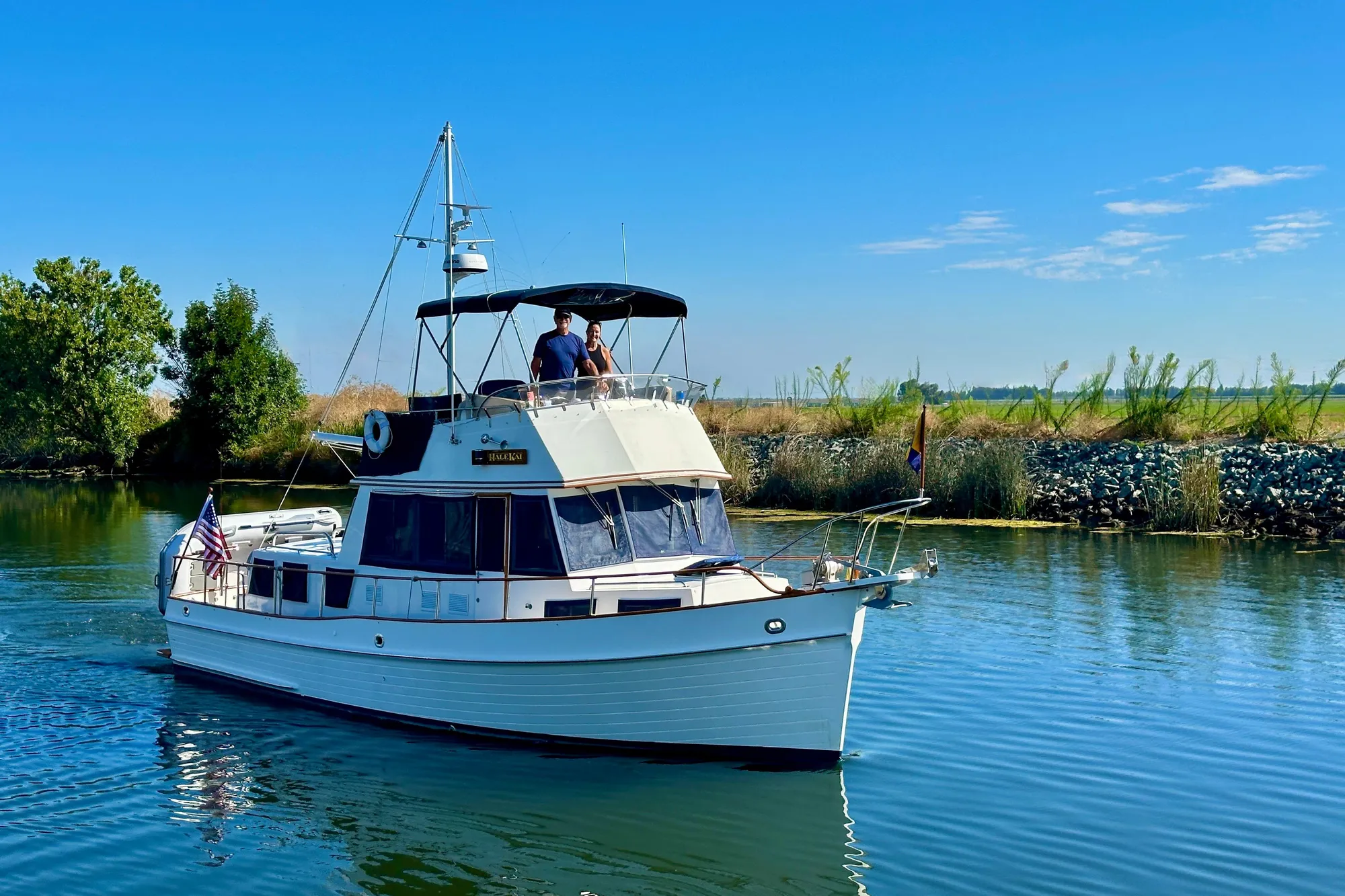 1997 Grand Banks Classic yacht cruising on a serene river under a clear blue sky.