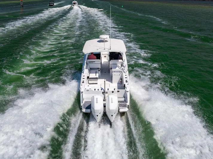  Yacht Photos Pics 2021 Blackfin 272 DC boat cruising on green water, rear view.