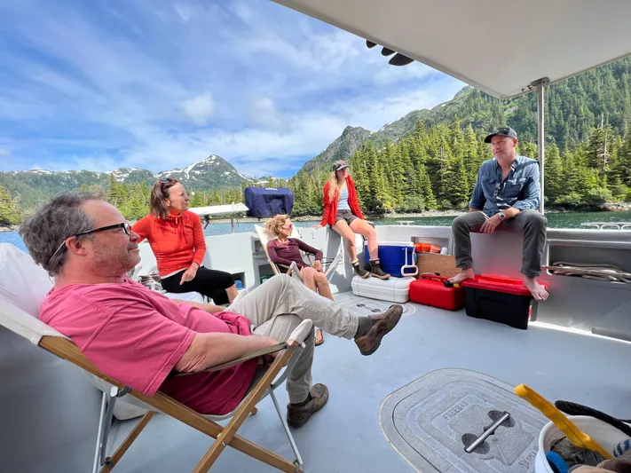 John Hunter Yacht Photos Pics People relaxing on a 2000 Nordic Tug 37 boat, surrounded by scenic mountains and forest.