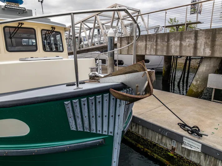 John Hunter Yacht Photos Pics Nordic Tug 37 (2000) docked, featuring a green hull and anchor at a marina.