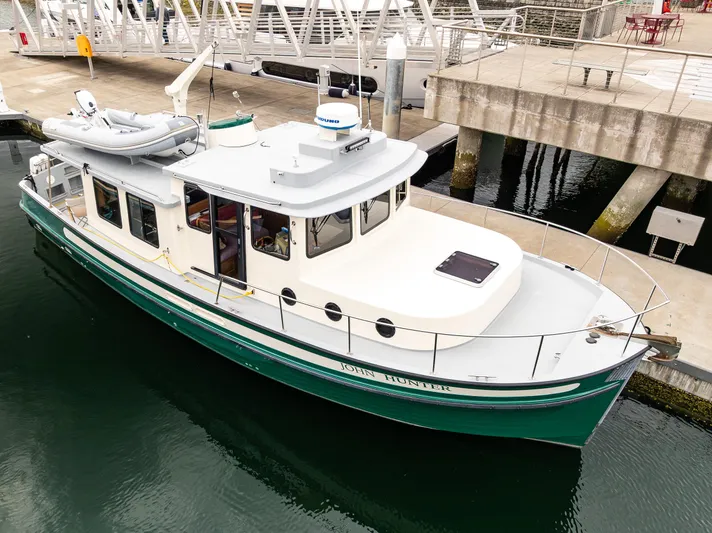 John Hunter Yacht Photos Pics 2000 Nordic Tug 37 docked at a marina, featuring a green hull and white deck.