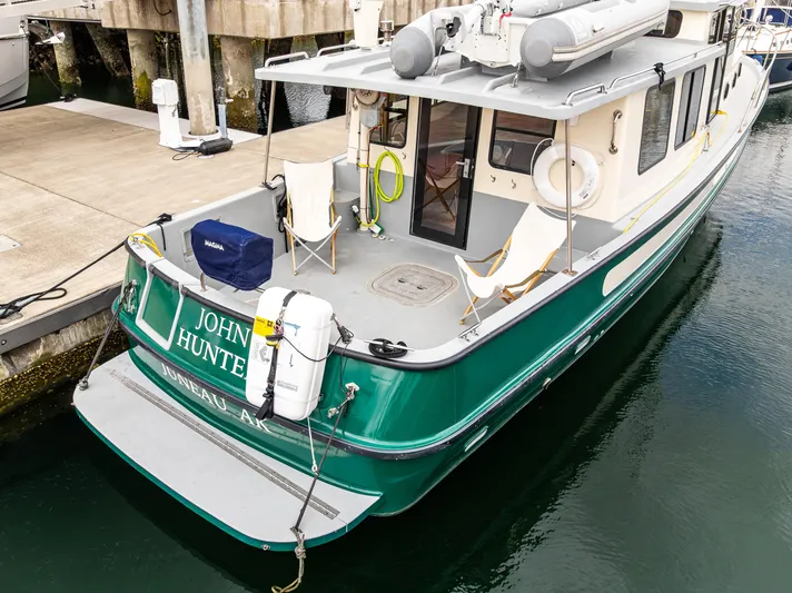 John Hunter Yacht Photos Pics 2000 Nordic Tug 37 docked, featuring green hull and deck chairs.