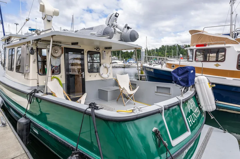 John Hunter Yacht Photos Pics 2000 Nordic Tug 37 docked at marina, featuring green hull and outdoor seating.
