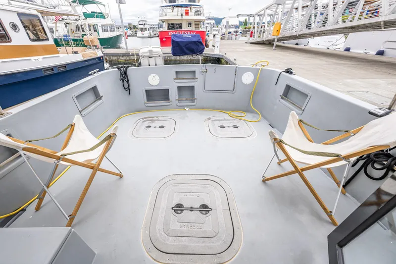 John Hunter Yacht Photos Pics Spacious deck of a 2000 Nordic Tug 37 with folding chairs and dock view.