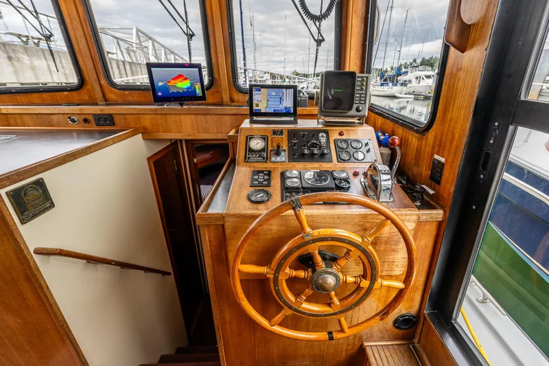 John Hunter Yacht Photos Pics Interior helm of a 2000 Nordic Tug 37, featuring wooden steering wheel and navigation equipment.