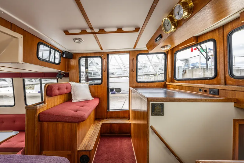 John Hunter Yacht Photos Pics Interior of a 2000 Nordic Tug 37, featuring wood paneling and red cushioned seating.