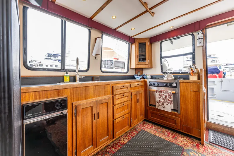 John Hunter Yacht Photos Pics Interior of a 2000 Nordic Tug 37 boat featuring a wooden kitchen with stove and sink.