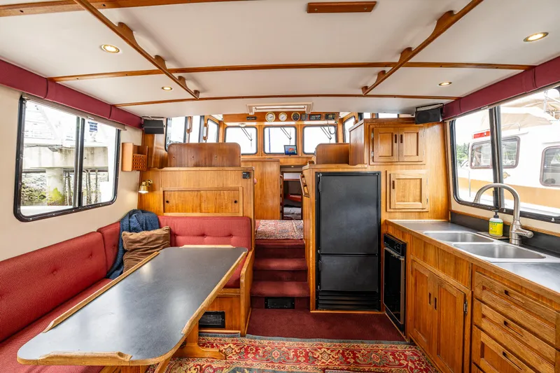 John Hunter Yacht Photos Pics Interior of a 2000 Nordic Tug 37, featuring a cozy seating area and wooden cabinetry.