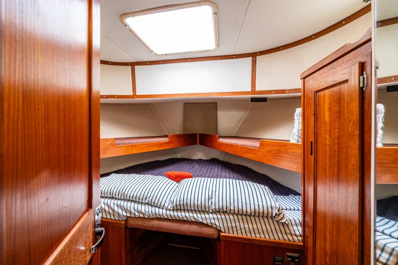 John Hunter Yacht Photos Pics Cozy cabin interior of 2000 Nordic Tug 37 with wooden finish and striped bedding.