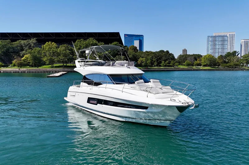  Yacht Photos Pics 2023 Prestige 460 Flybridge yacht cruising on a serene lake with city skyline backdrop.