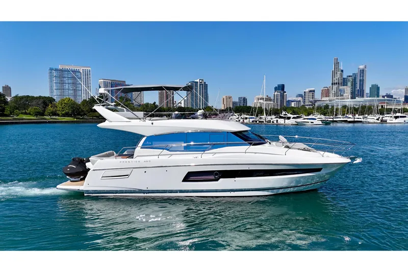  Yacht Photos Pics 2023 Prestige 460 Flybridge yacht cruising near city skyline and marina.