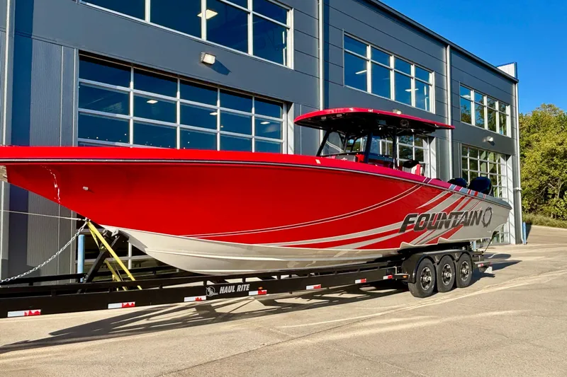  Yacht Photos Pics 2021 Fountain 38 SC boat in vibrant red, parked on a trailer outside a modern building.