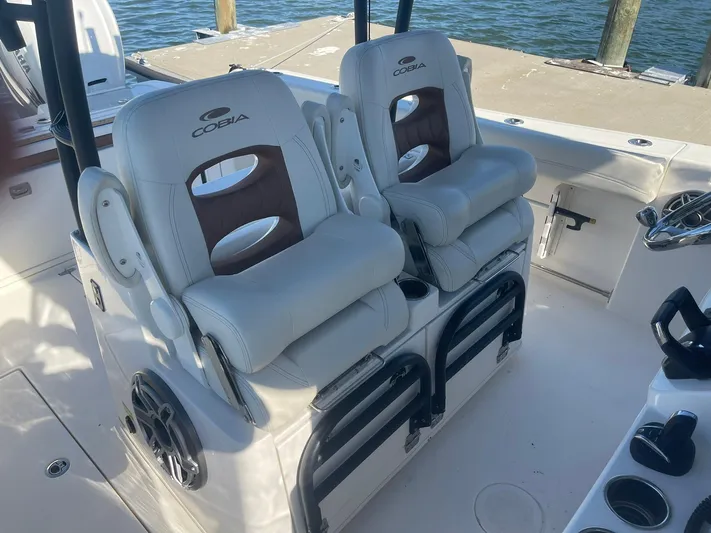  Yacht Photos Pics 2023 Cobia 320 CC boat interior with dual cushioned seats by the water.