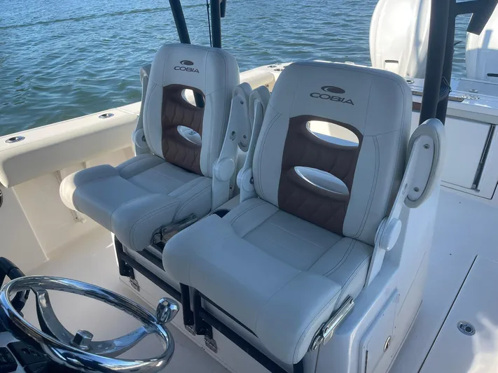  Yacht Photos Pics 2023 Cobia 320 CC boat seats with steering wheel, on calm water.