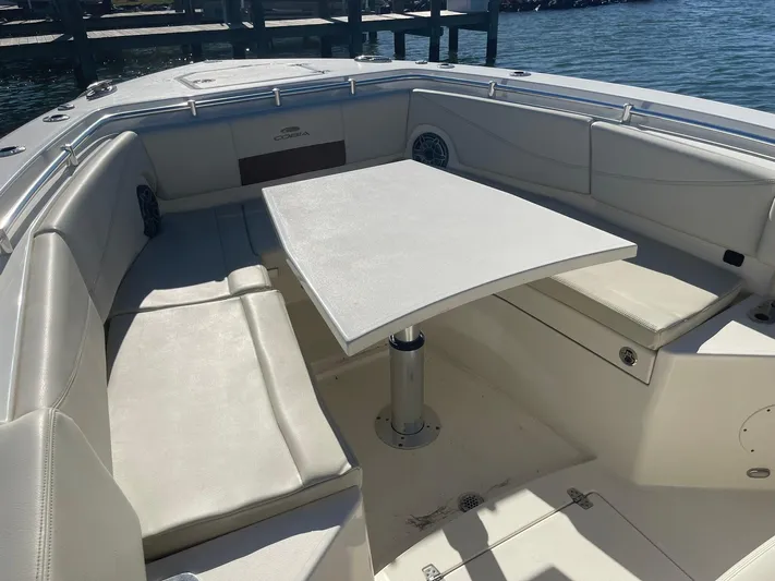  Yacht Photos Pics 2023 Cobia 320 CC boat interior with seating and table, dockside view.
