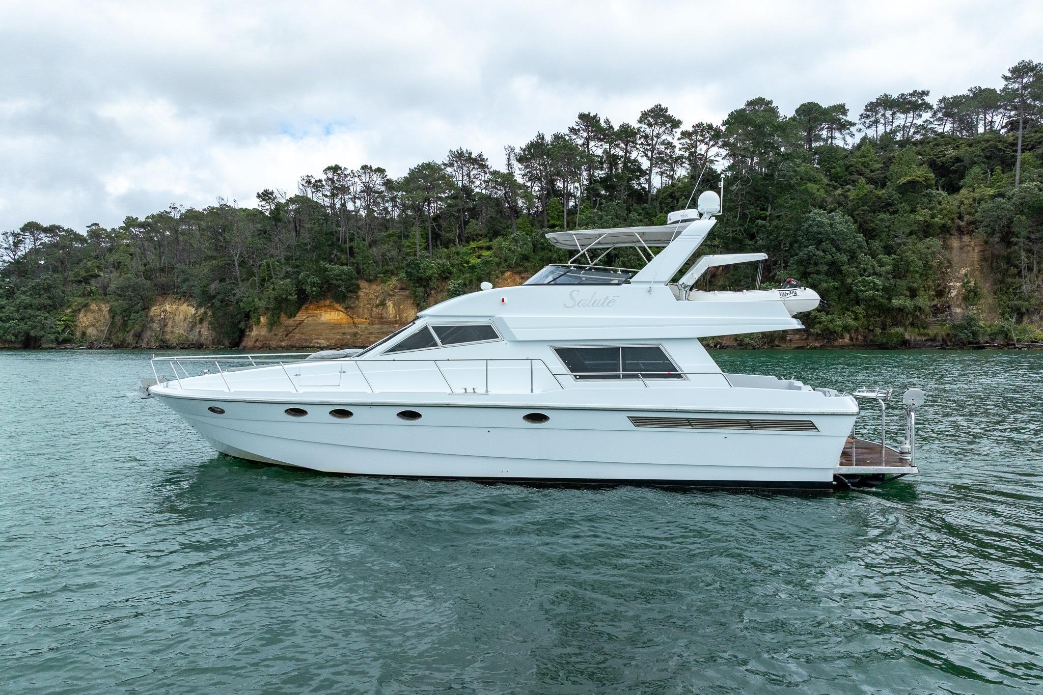 1995 Comar Clanship 52 yacht on serene water with lush forest backdrop.