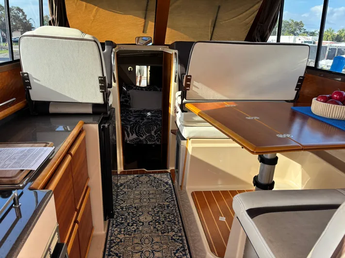 Y Knot Yacht Photos Pics 2017 Cutwater C-28 Deluxe interior with dining area, wooden cabinetry, and cozy seating.