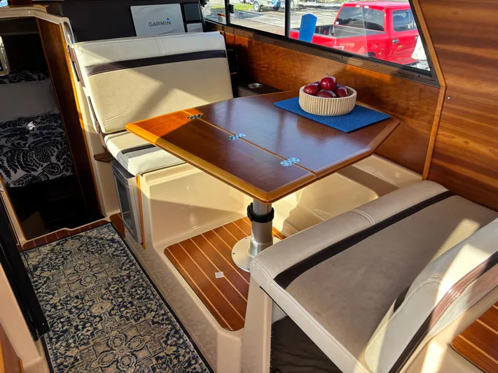 Y Knot Yacht Photos Pics Interior of 2017 Cutwater C-28 Deluxe boat with dining area and wooden table.