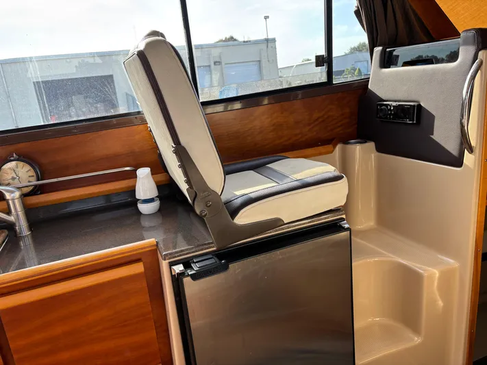 Y Knot Yacht Photos Pics 2017 Cutwater C-28 Deluxe interior with seat, fridge, and wooden cabinetry.