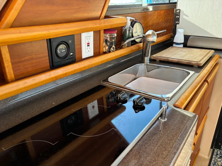 Y Knot Yacht Photos Pics 2017 Cutwater C-28 Deluxe kitchen with sink, stove, and wooden cabinetry.
