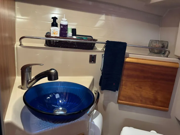Y Knot Yacht Photos Pics 2017 Cutwater C-28 Deluxe bathroom with blue glass sink and wooden cabinet.