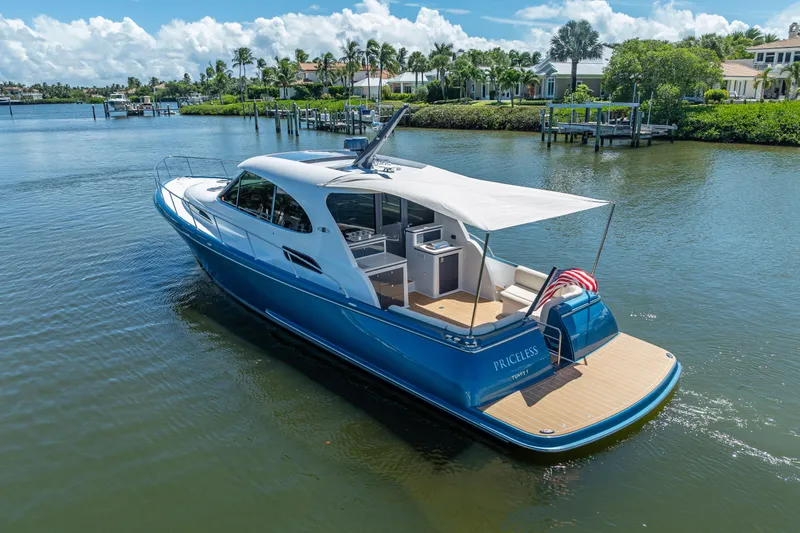 Priceless Yacht Photos Pics 2019 Palm Beach Motor Yachts GT50 cruising on a serene waterway, surrounded by lush greenery.