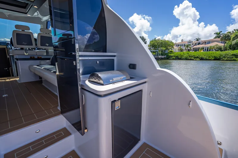 Priceless Yacht Photos Pics 2019 Palm Beach Motor Yachts GT50 interior with seating and outdoor grill by the water.