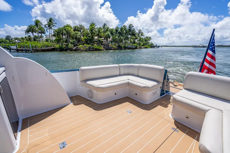 Priceless Yacht Photos Pics 2019 Palm Beach Motor Yachts GT50 deck with seating, American flag, and scenic waterfront view.