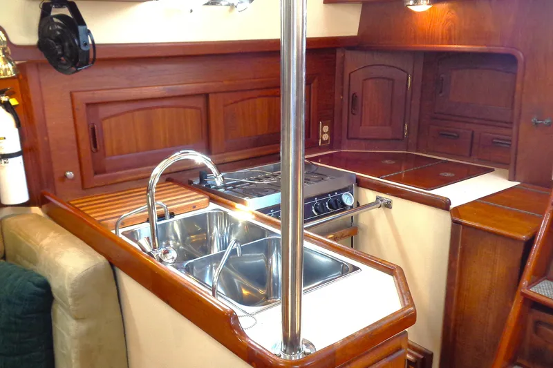 Adventure Yacht Photos Pics Interior of 1995 Pacific Seacraft 37 yacht kitchen with sink, stove, and wooden cabinetry.