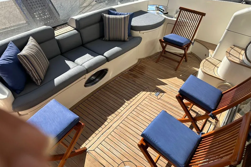 Chica Loca Yacht Photos Pics Luxurious 2003 Azimut 55E yacht deck with cushioned seating and wooden chairs.