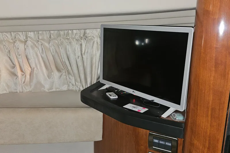 N/a Yacht Photos Pics Interior of 2004 Sea Ray 380 Sundancer with TV and remote on wooden shelf.