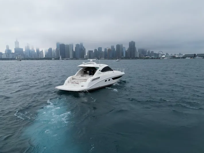 Cabby 13 Yacht Photos Pics 2013 Sea Ray 470 Sundancer yacht cruising near a city skyline on a cloudy day.