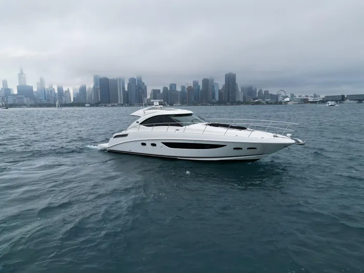 Cabby 13 Yacht Photos Pics 2013 Sea Ray 470 Sundancer yacht cruising near a city skyline on a cloudy day.