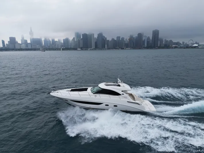 Cabby 13 Yacht Photos Pics 2013 Sea Ray 470 Sundancer yacht cruising near a city skyline on a cloudy day.