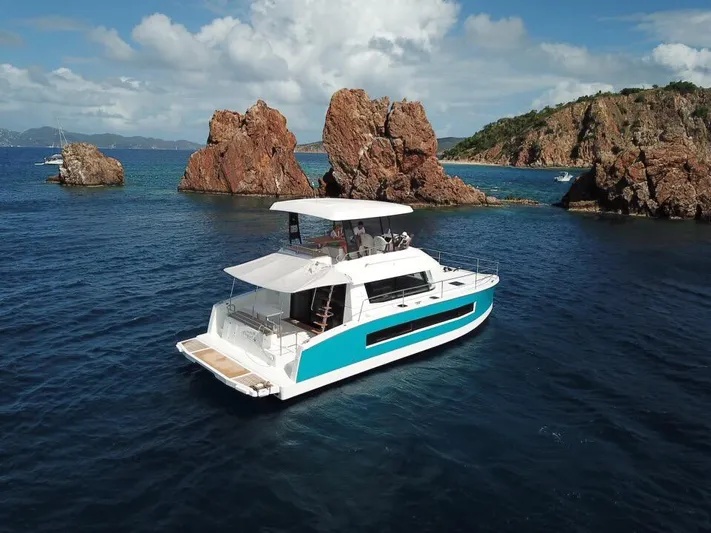 Yacht Photos Pics 2019 Fountaine Pajot MY 37 yacht cruising near rocky islands under a clear sky.
