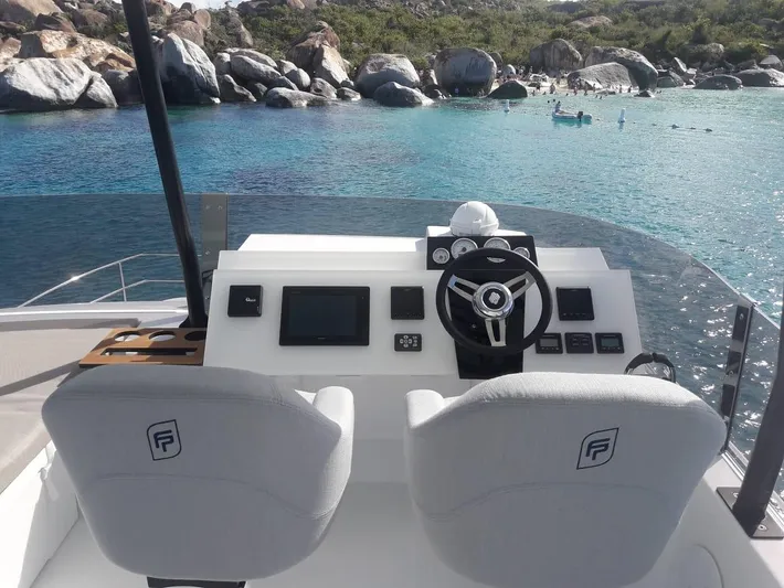  Yacht Photos Pics Helm of 2019 Fountaine Pajot MY 37 yacht overlooking serene turquoise waters and rocky shoreline.