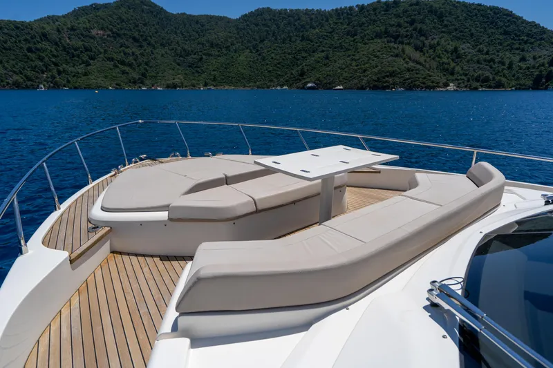 Dudu Yacht Photos Pics Luxurious 2021 Ferretti Yachts 550 deck with seating, overlooking serene blue waters and lush hills.