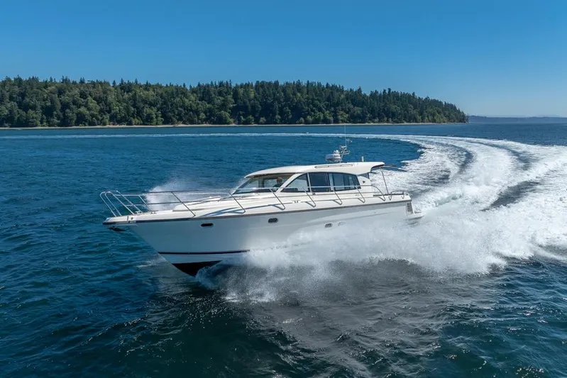 Treasure State Yacht Photos Pics Nimbus 405 Coup&eacute; 2022 cruising on open water with forested shoreline in background.