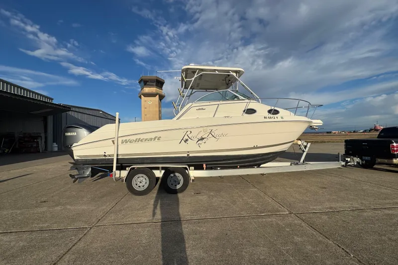  Yacht Photos Pics 2009 Wellcraft 270 Coastal O/B boat on trailer, parked outdoors under a blue sky.
