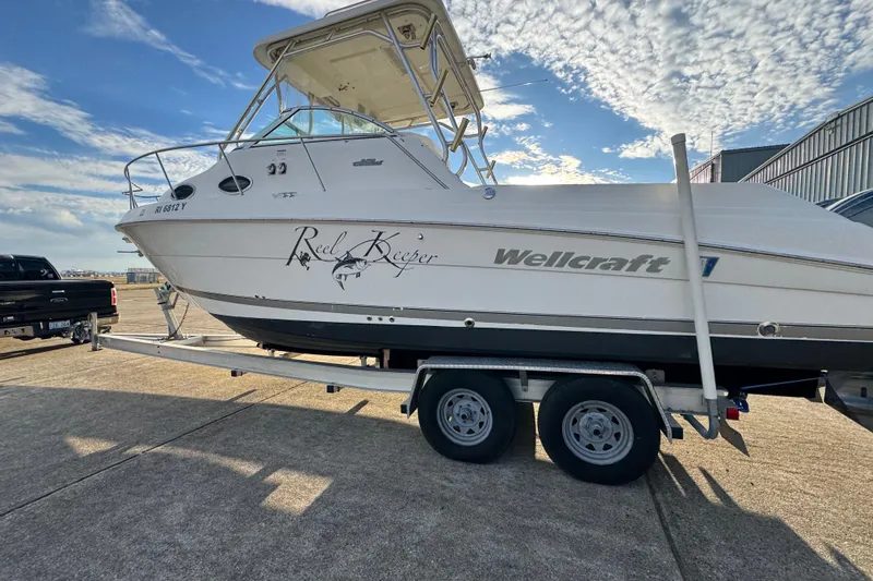  Yacht Photos Pics 2009 Wellcraft 270 Coastal O/B boat on trailer under a partly cloudy sky.