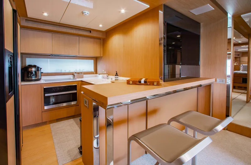 Lady Elkie Yacht Photos Pics Modern kitchen interior on a 2016 Riva 88' Florida yacht, featuring sleek wood finishes and bar seating.