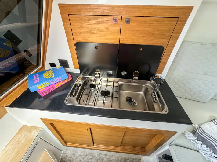  Yacht Photos Pics 2024 De Antonio Yachts D28 Cruiser kitchen area with sink and stove, featuring wooden cabinetry.
