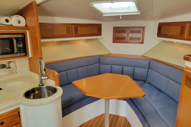 Reely Blessed Yacht Photos Pics 1998 Cabo 31 Express cabin interior with blue seating, wooden table, and kitchenette.
