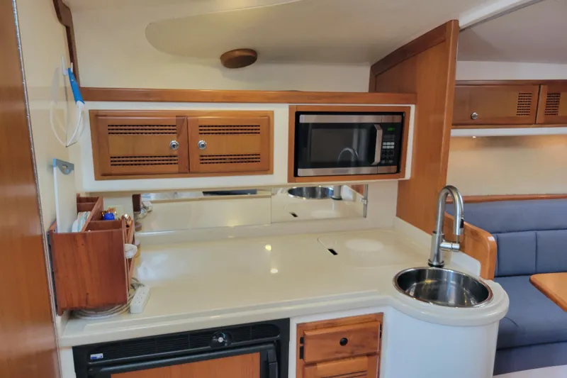 Reely Blessed Yacht Photos Pics 1998 Cabo 31 Express boat interior with kitchenette, microwave, sink, and wooden cabinetry.
