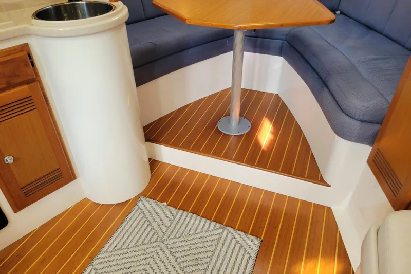 Reely Blessed Yacht Photos Pics 1998 Cabo 31 Express interior with wood flooring, cushioned seating, and compact table.
