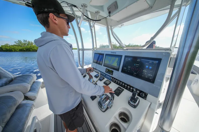  Yacht Photos Pics Person navigating a 2020 Tideline 365 Offshore boat with advanced control panel.