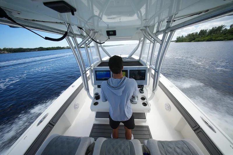  Yacht Photos Pics Person steering a 2020 Tideline 365 Offshore boat on a scenic waterway.