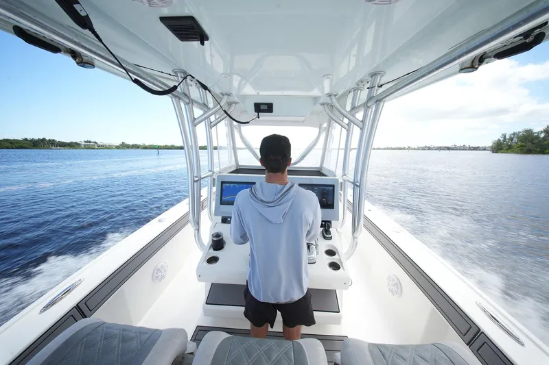  Yacht Photos Pics Person steering 2020 Tideline 365 Offshore boat on open water.